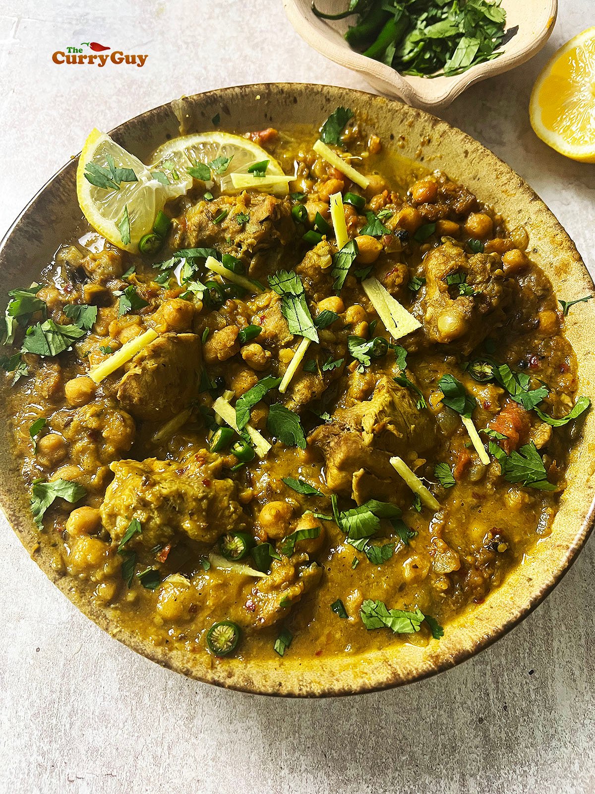 Chicken and chickpea curry garnished with lemon, chillies, coriander (cilantro) and julienned ginger. 