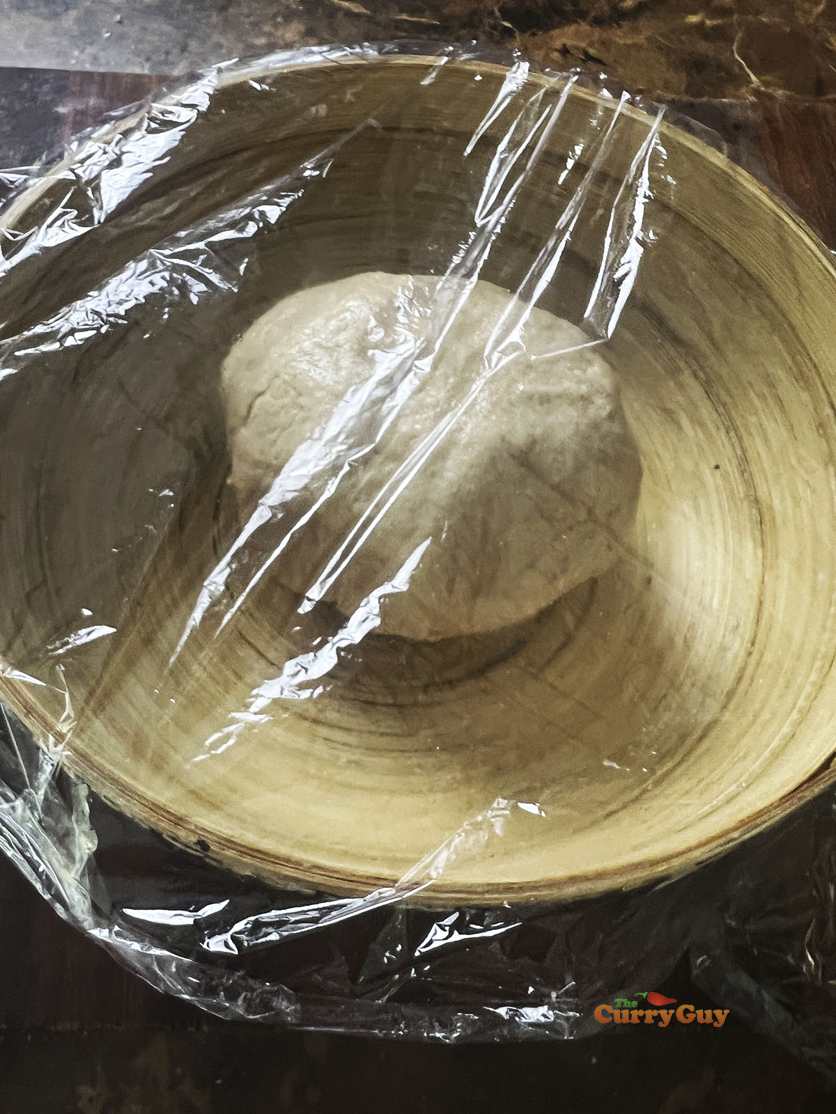 Dough ball in bowl covered with clingfilm.