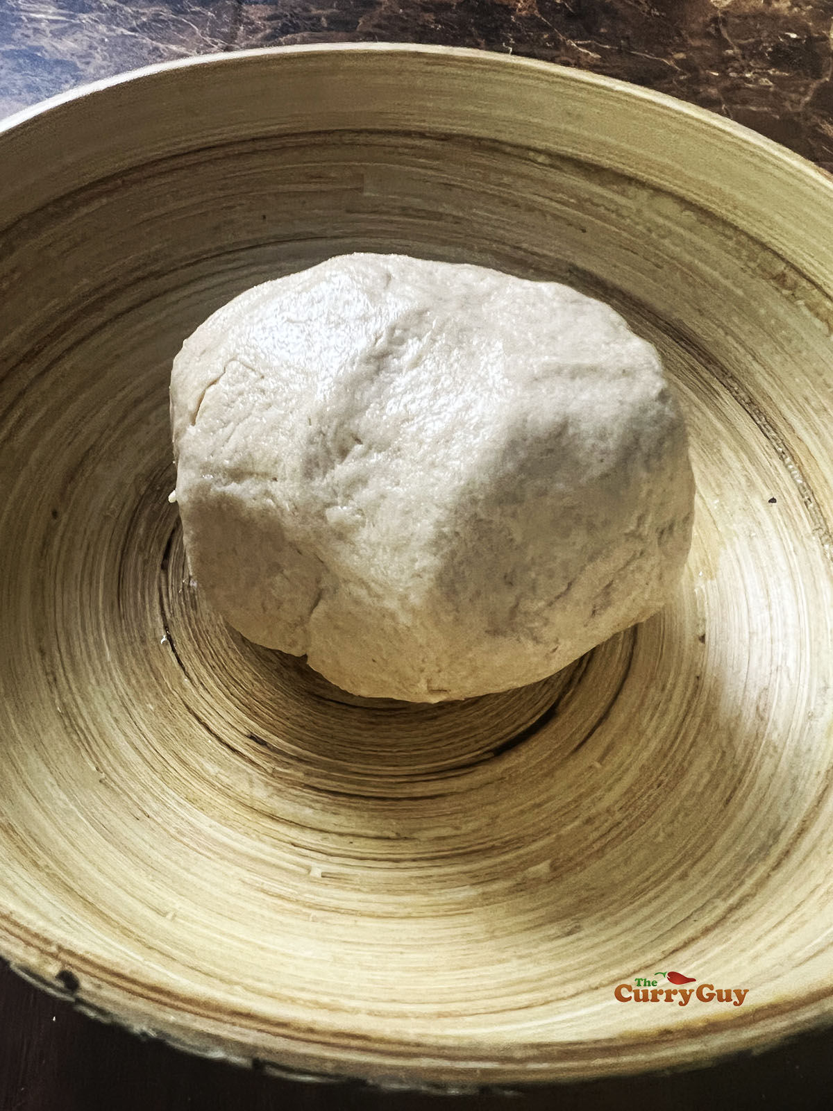 Placing the dough ball back into the bowl.