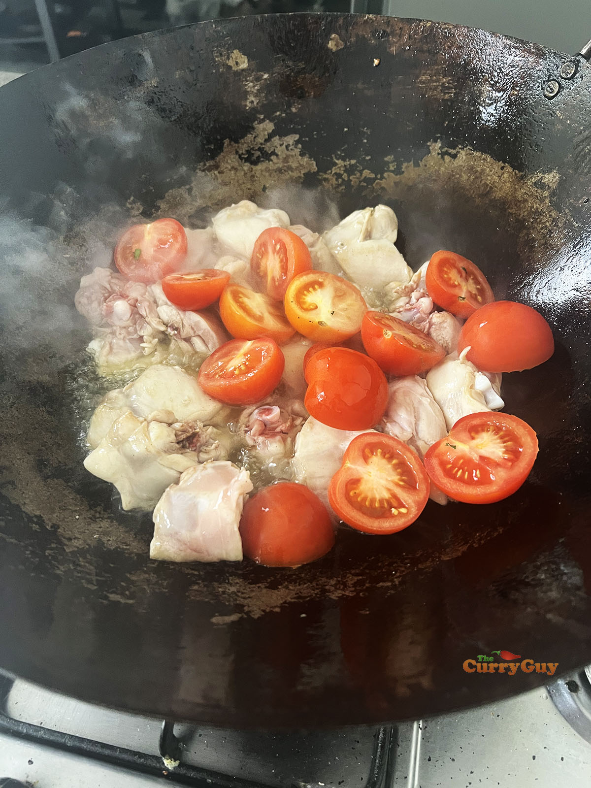 Adding tomatoes to the chicken and oil.