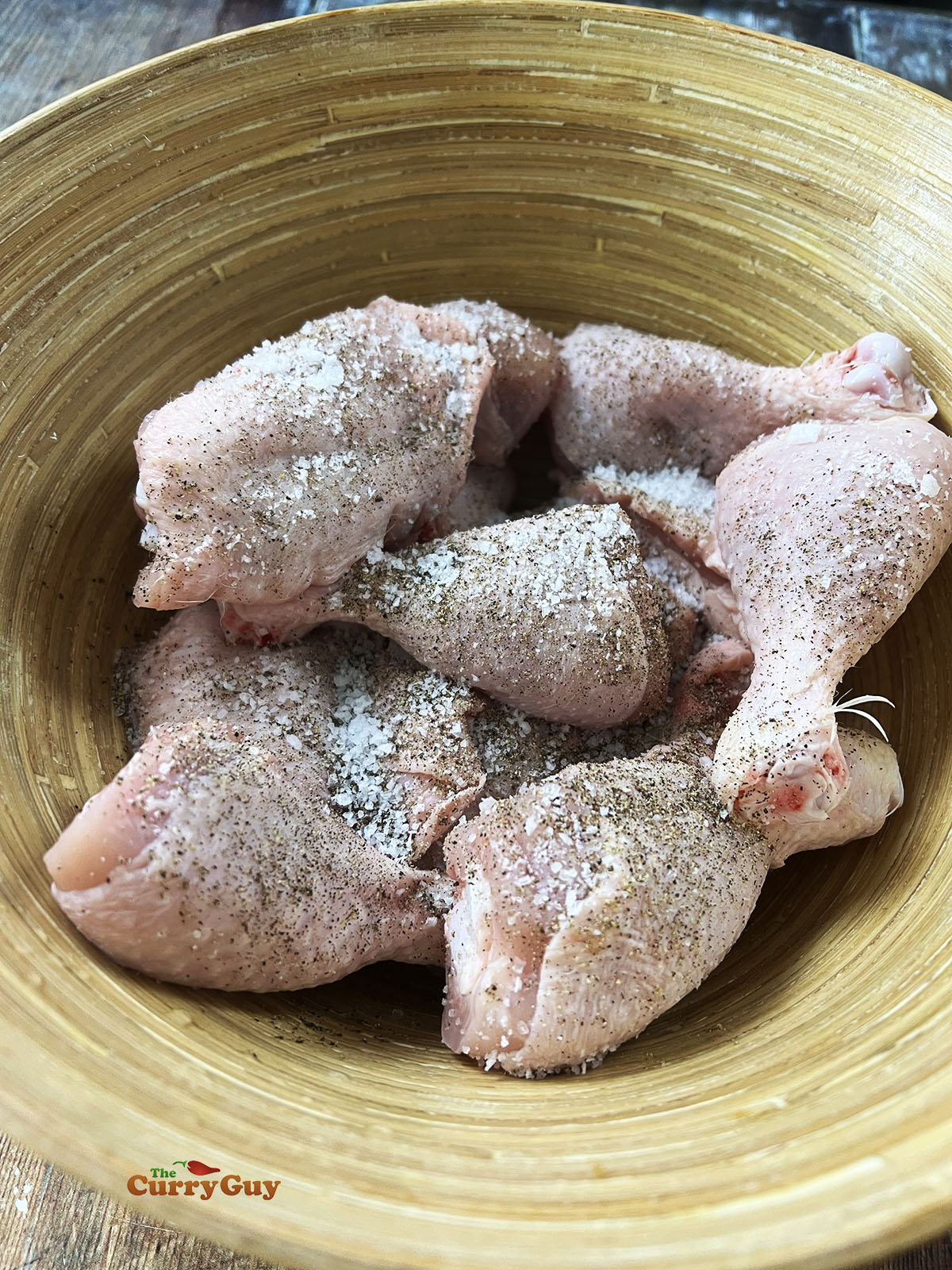 Seasoning the chicken with salt and pepper.