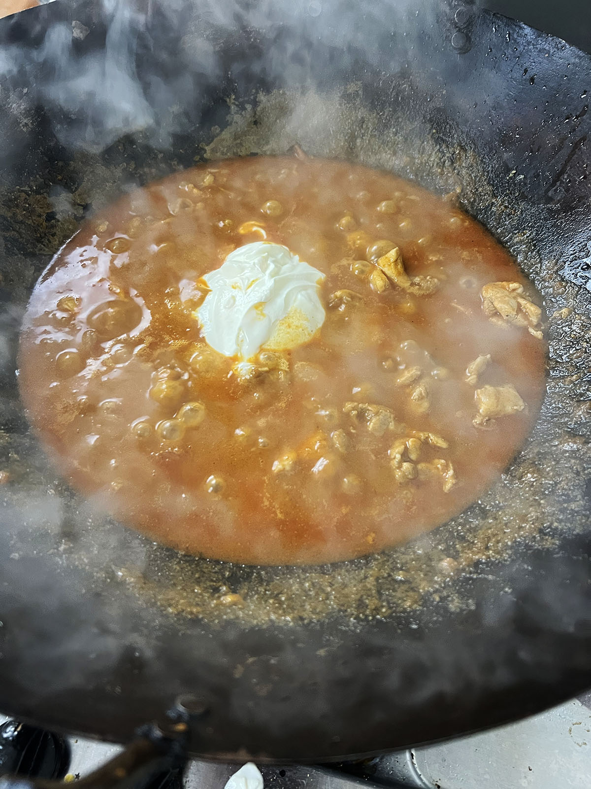 Adding yoghurt to the butter chicken karahi.