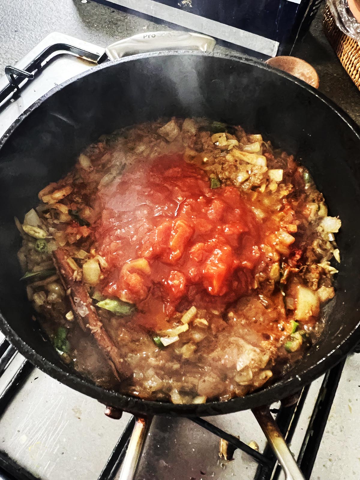 Adding the water or stock and the chopped tomatoes to the pan.
