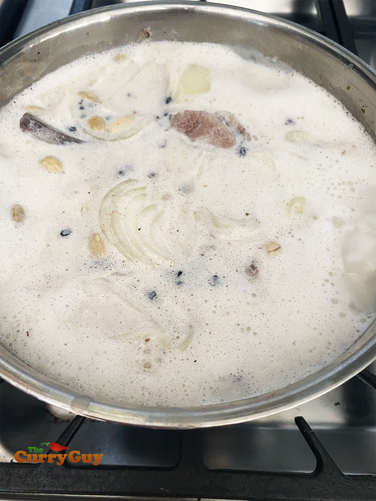 Simmering the lamb chops with the whole spices in milk.