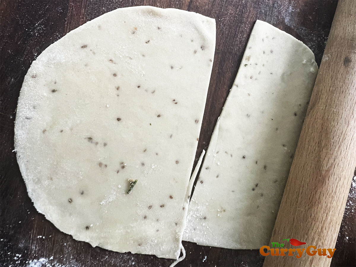Slicing a round of samosa pastry into two halves.