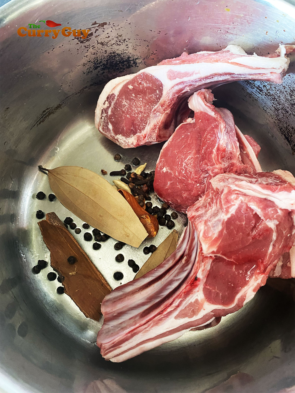 The lamb chops in a pot with the whole spices.