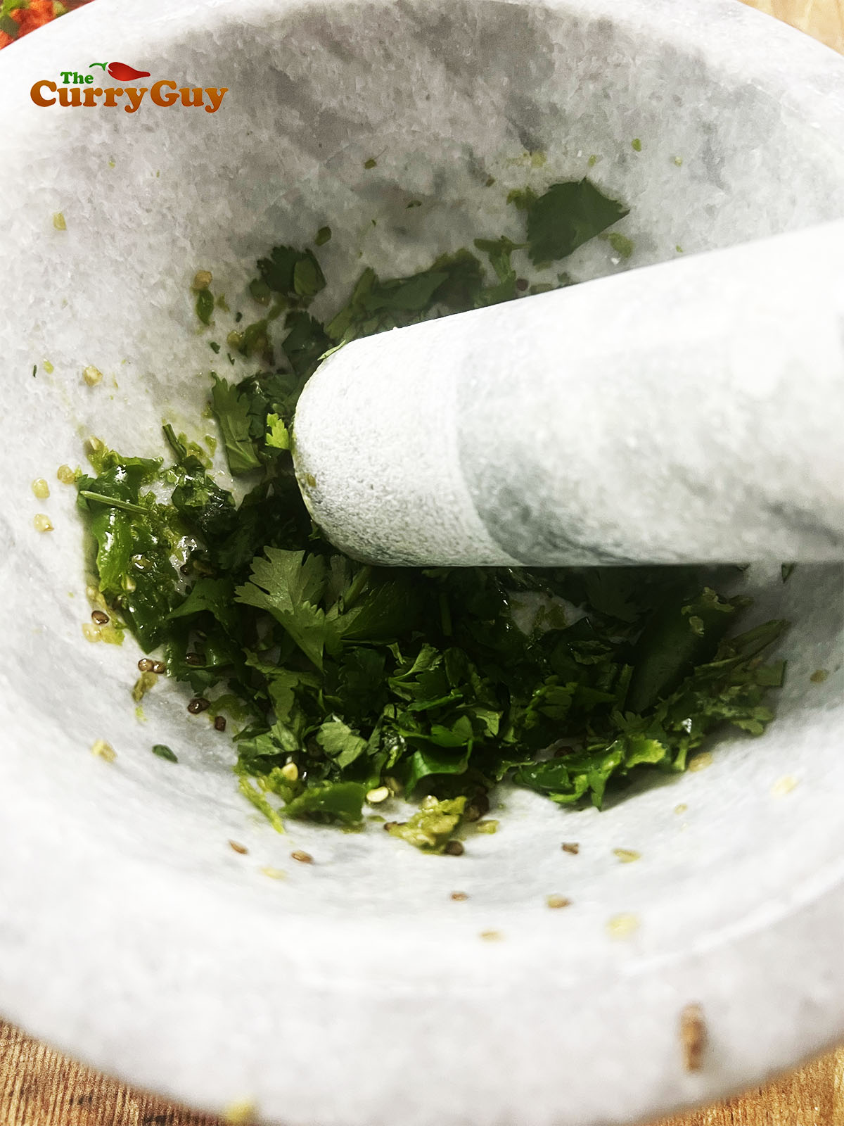 Pounding the chillies and coriander (cilantro) into a paste.
