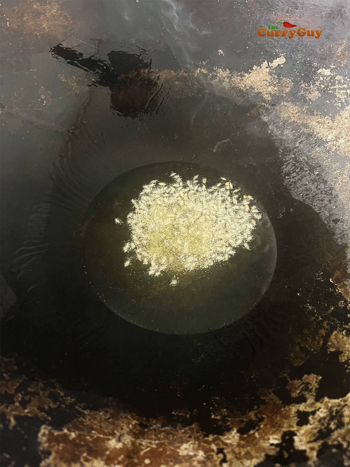 Infusing whole spices into the oil in the karahi