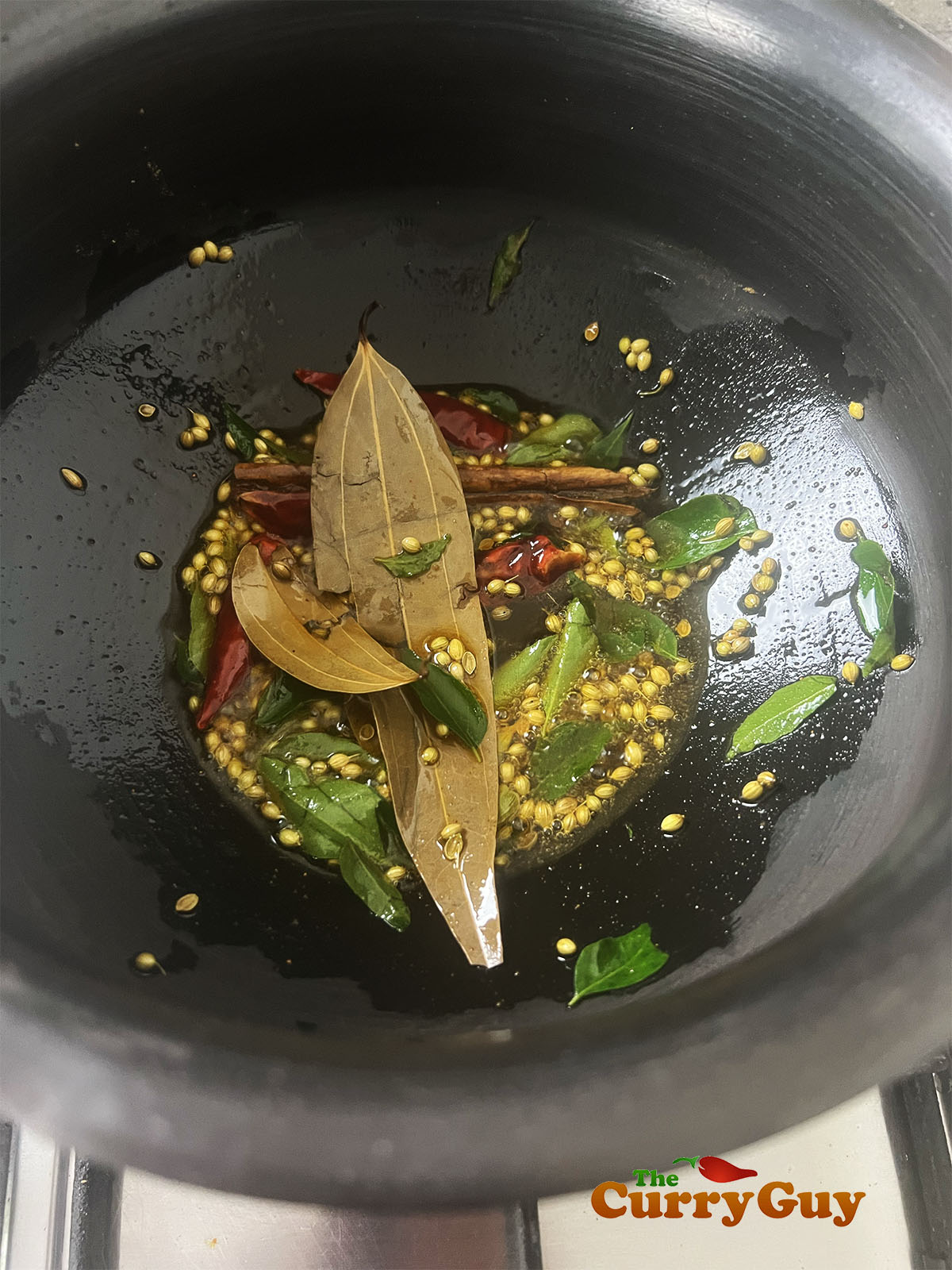Frying the whole spices and curry leaves.