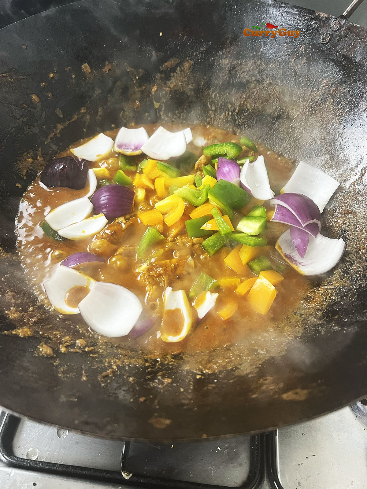 Adding the chopped vegetables to the karahi