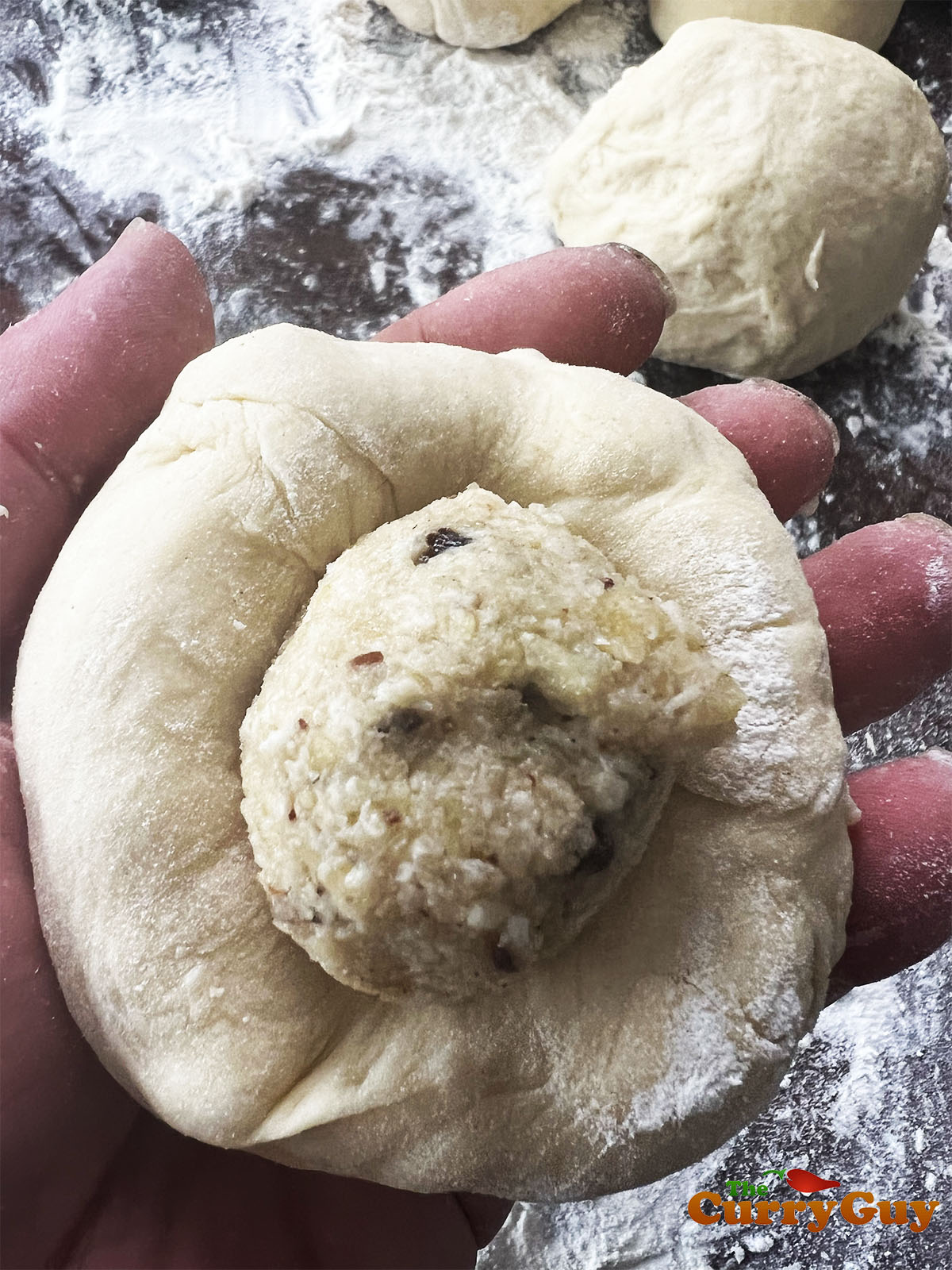 Adding the Peshwari filling to the dough balls.
