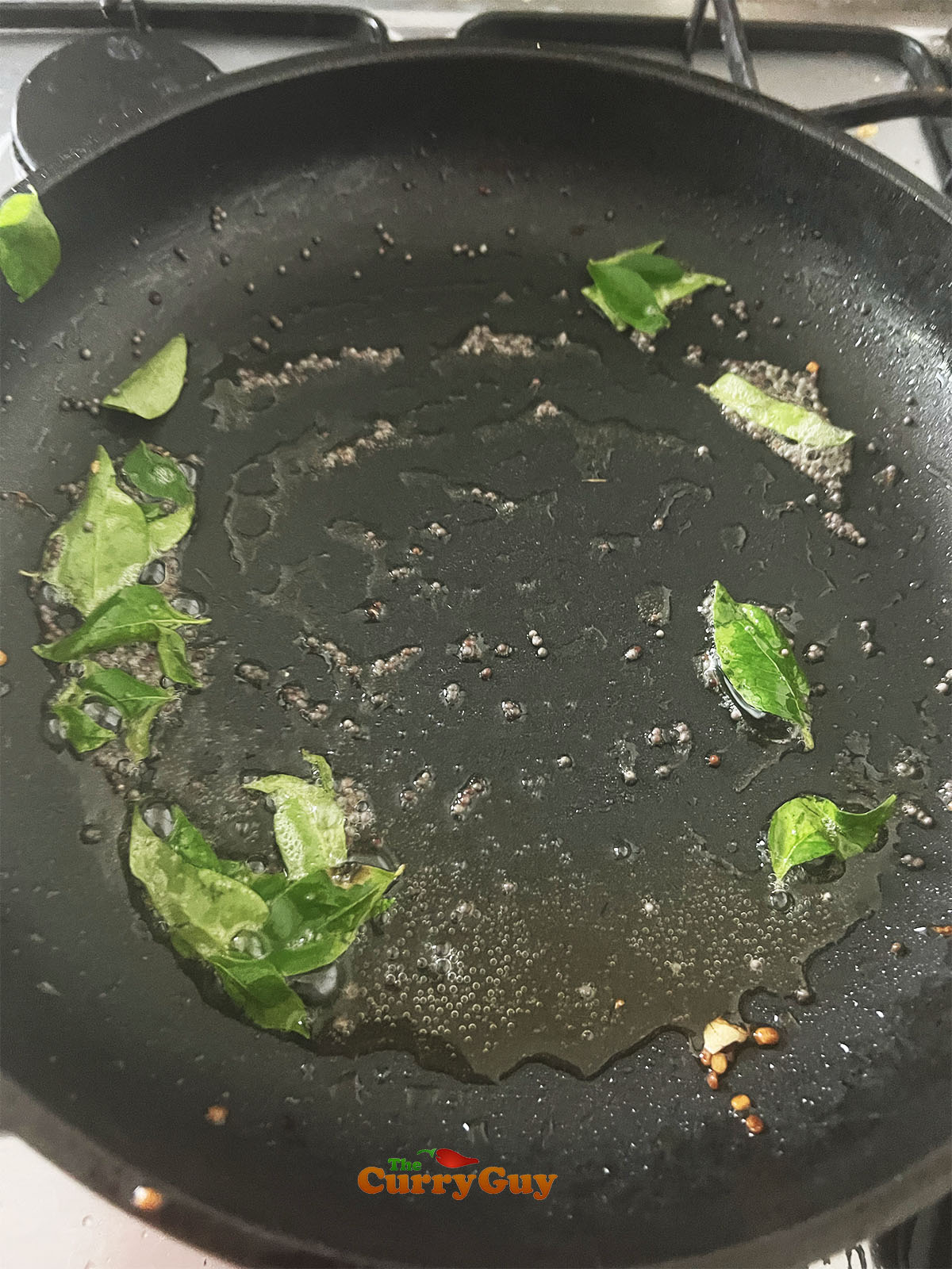 Heating the remaining oil to fry the mustard seeds and curry leaves.