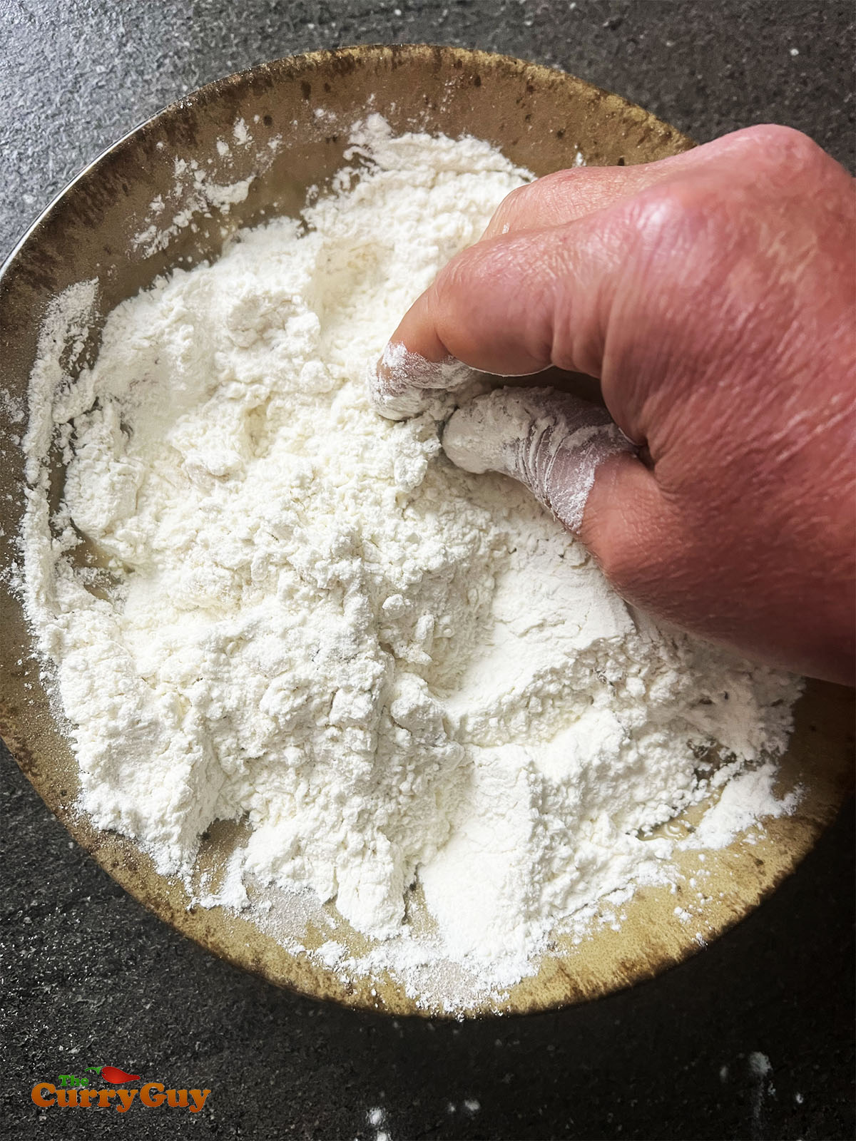 Adding water and seasoning to the samosa dough.