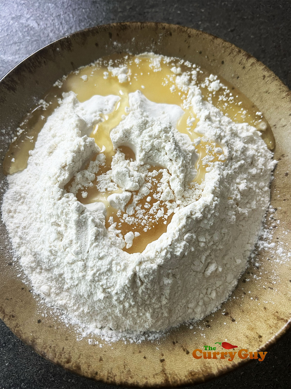 Adding oil to the flour and salt for the samosa pastry.