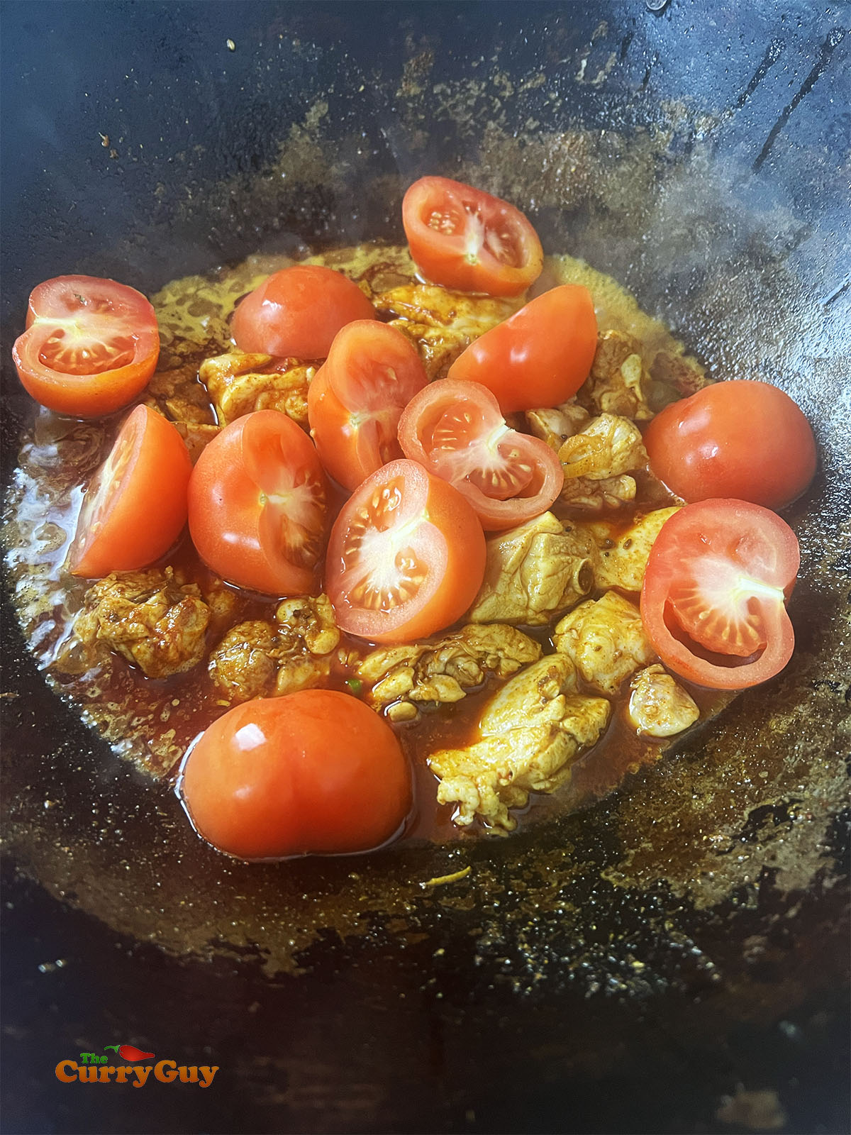 Adding the tomatoes to halved tomatoes to the curry