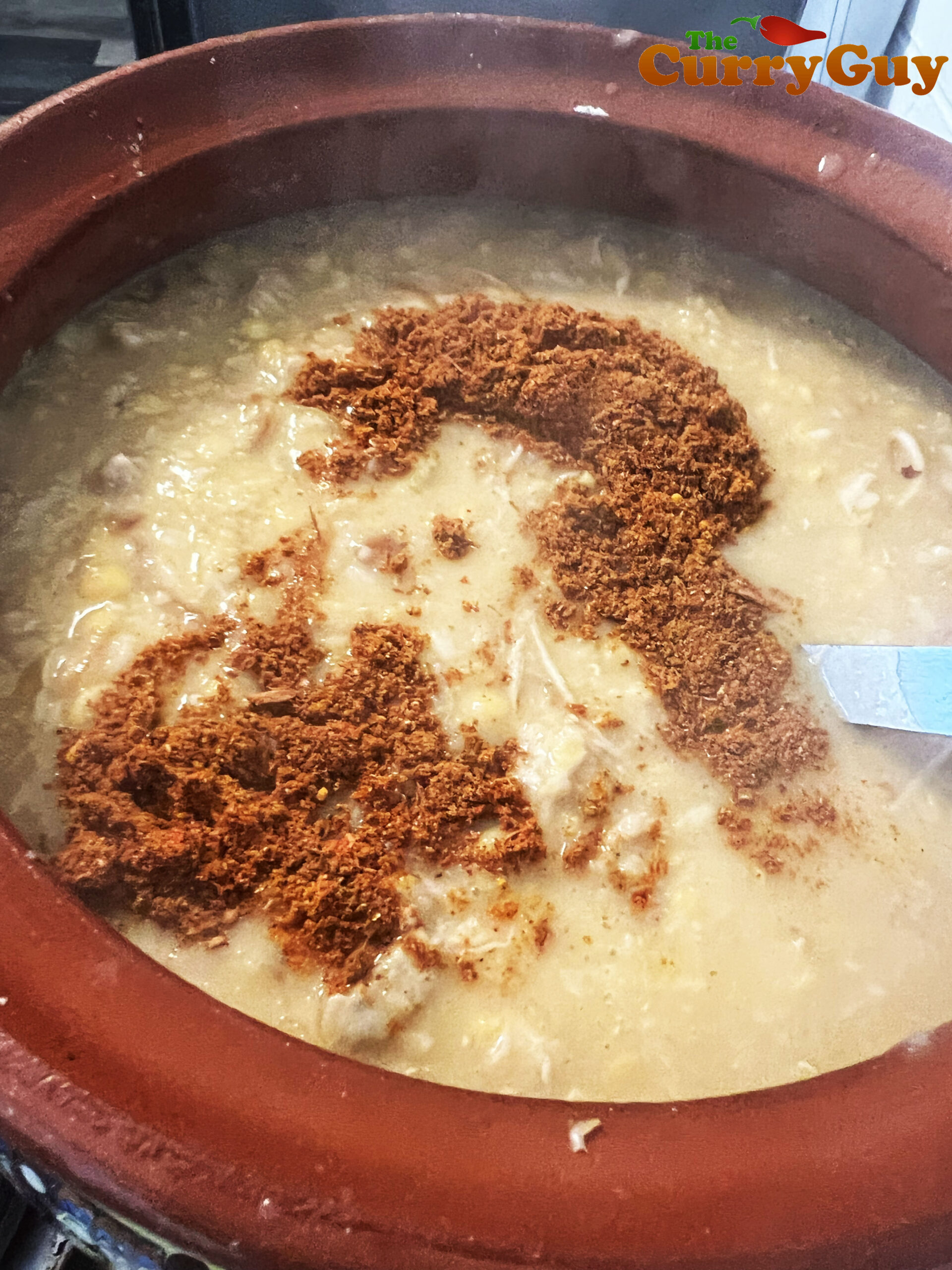 Stirring salt and the haleem spice blend into the chicken haleem.