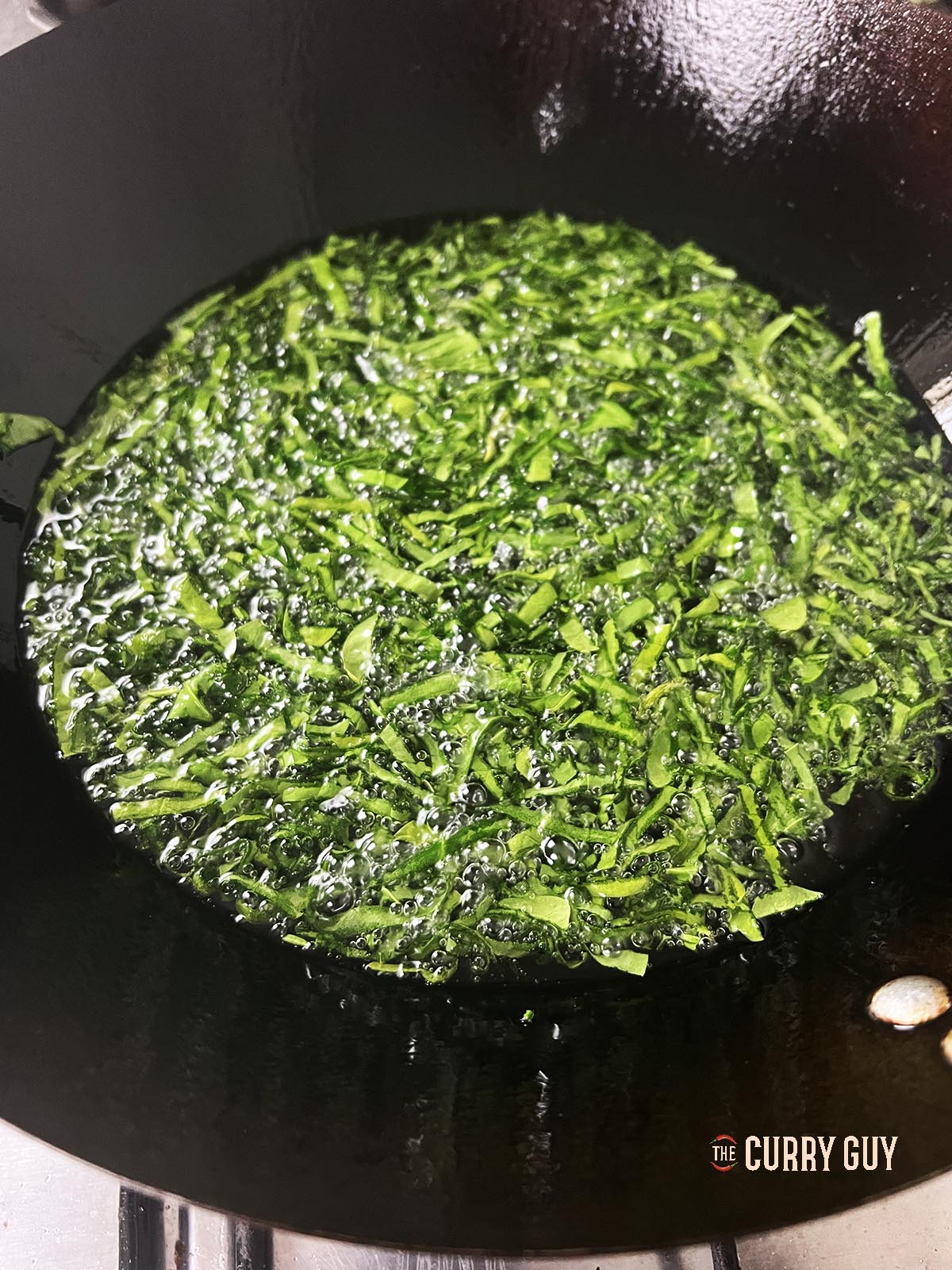 The spinach continuing to fry.
