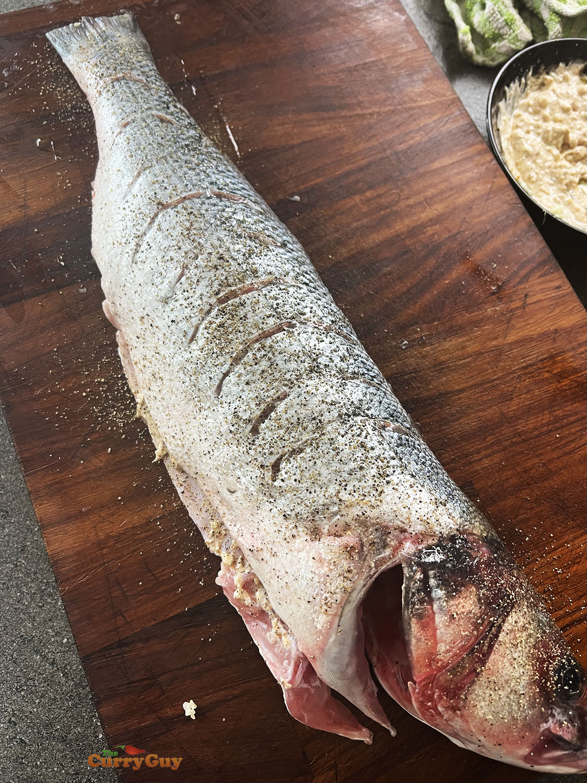 Fish with scored skin and seasoned with salt and pepper.