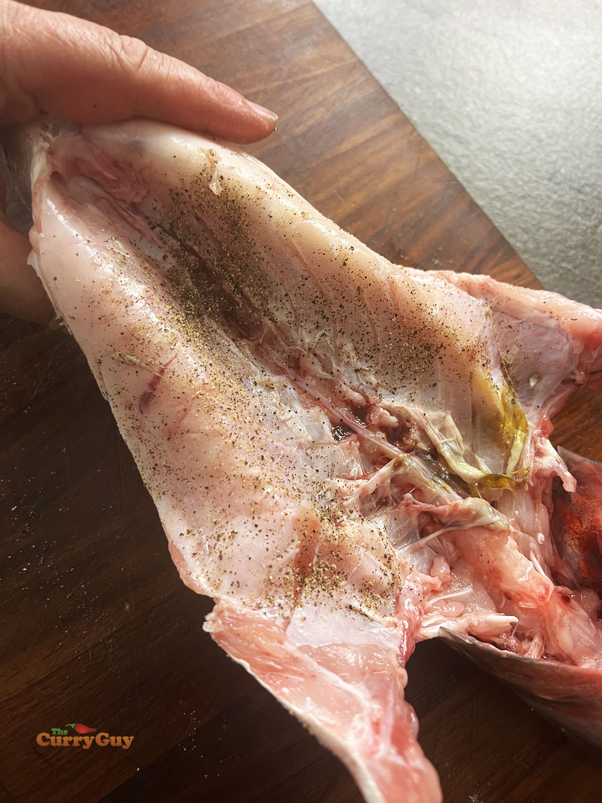 Seasoning the inside of the fish with salt and pepper.