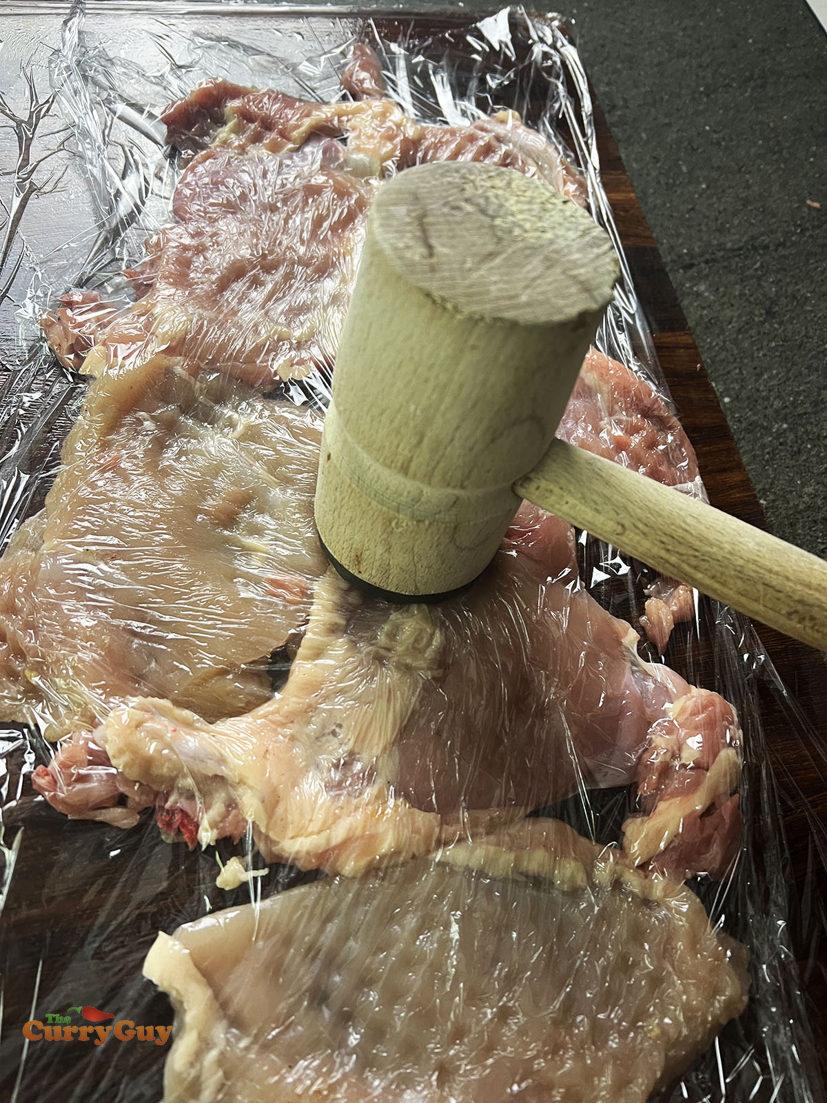 Pounding the chicken with a meat mallet.