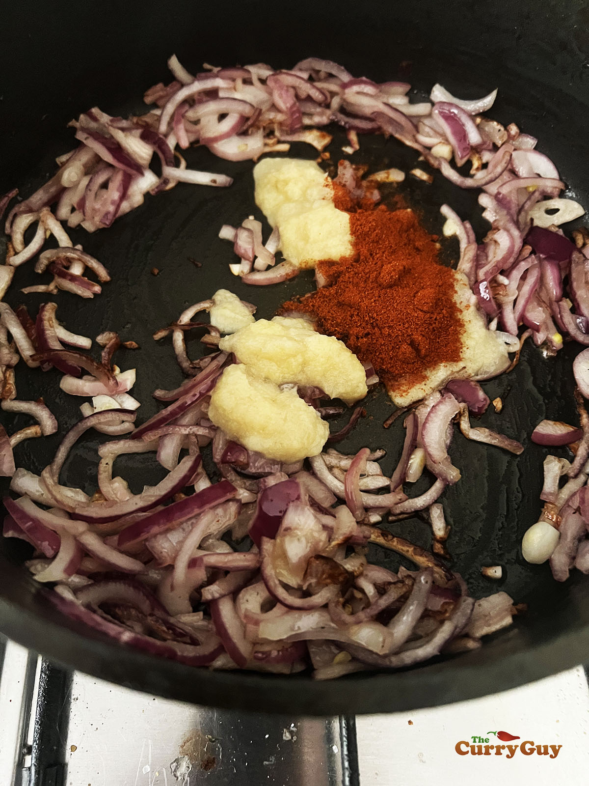 Adding garlic and ginger paste along with chilli powder to the pan.