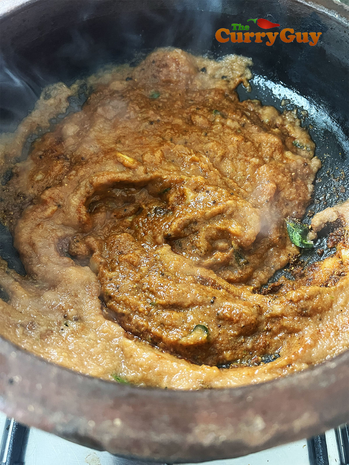 Adding the blended onion and tomatoes to the curry.