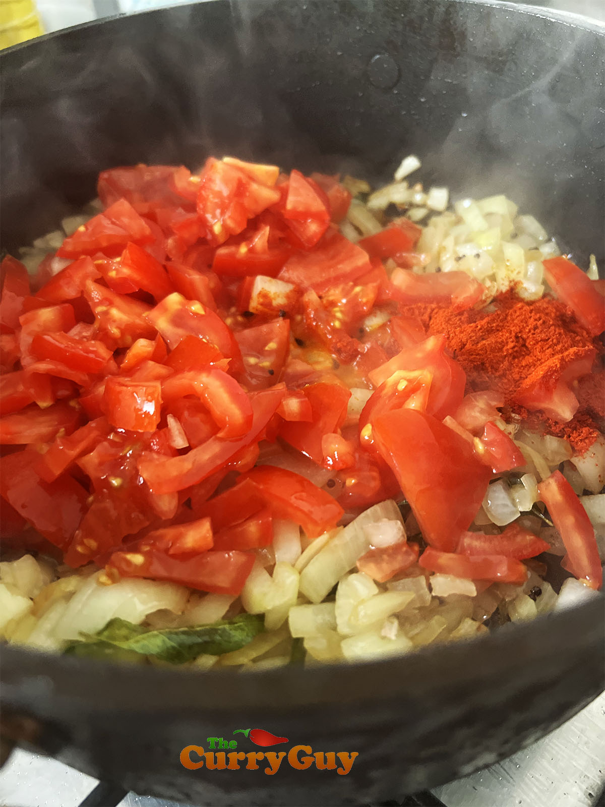 Adding chopped tomatoes to the pan.