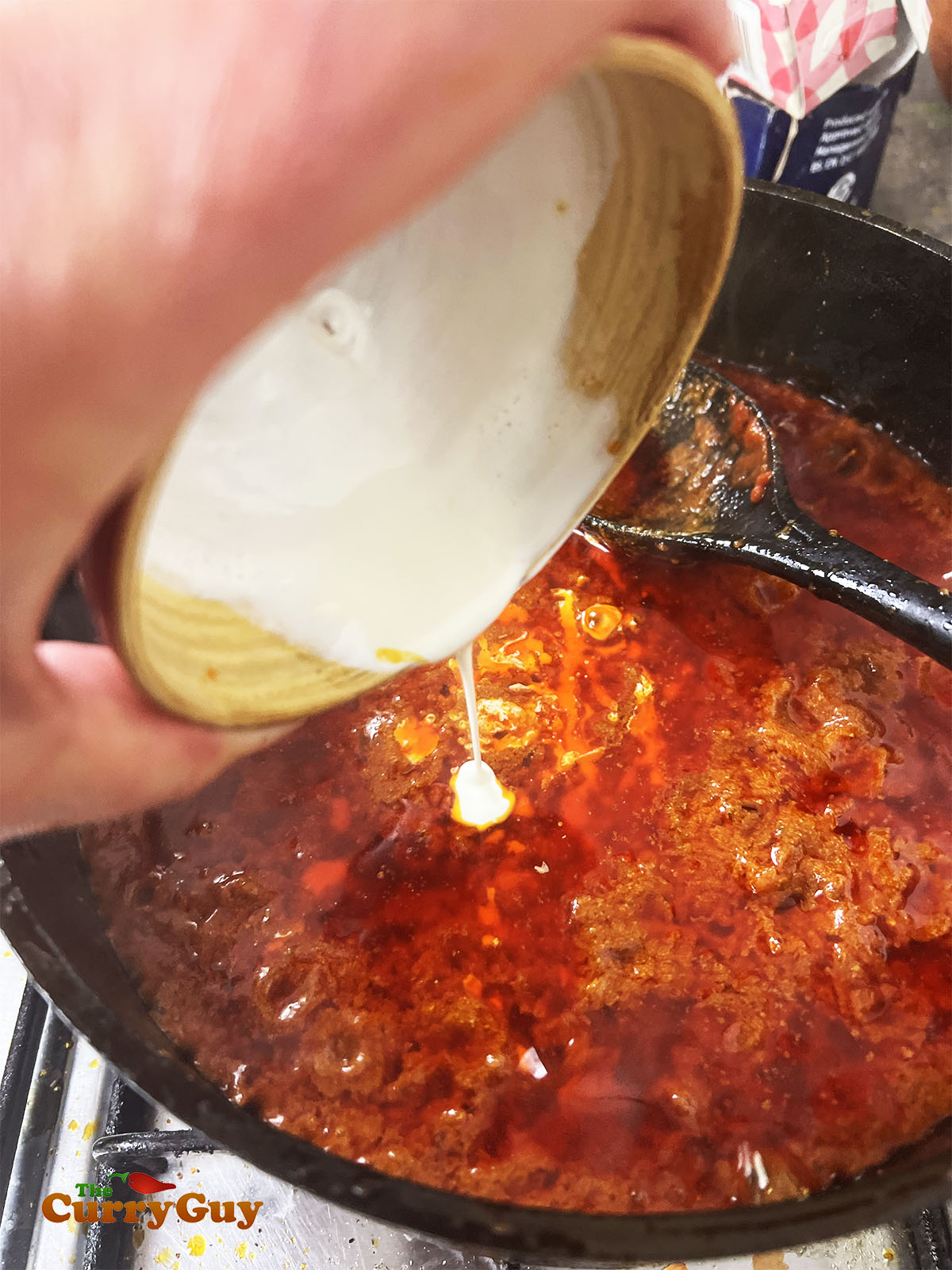 Adding the cream to the chicken changezi.