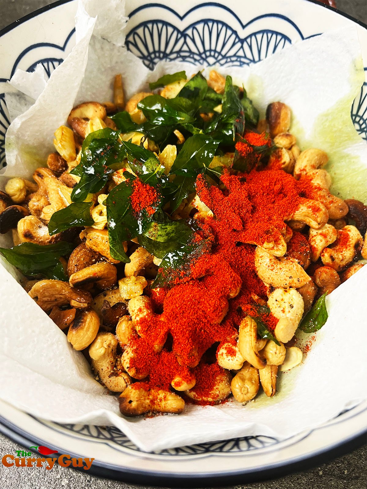Adding the spices, garlic, curry leaves, salt and pepper to the cashews.