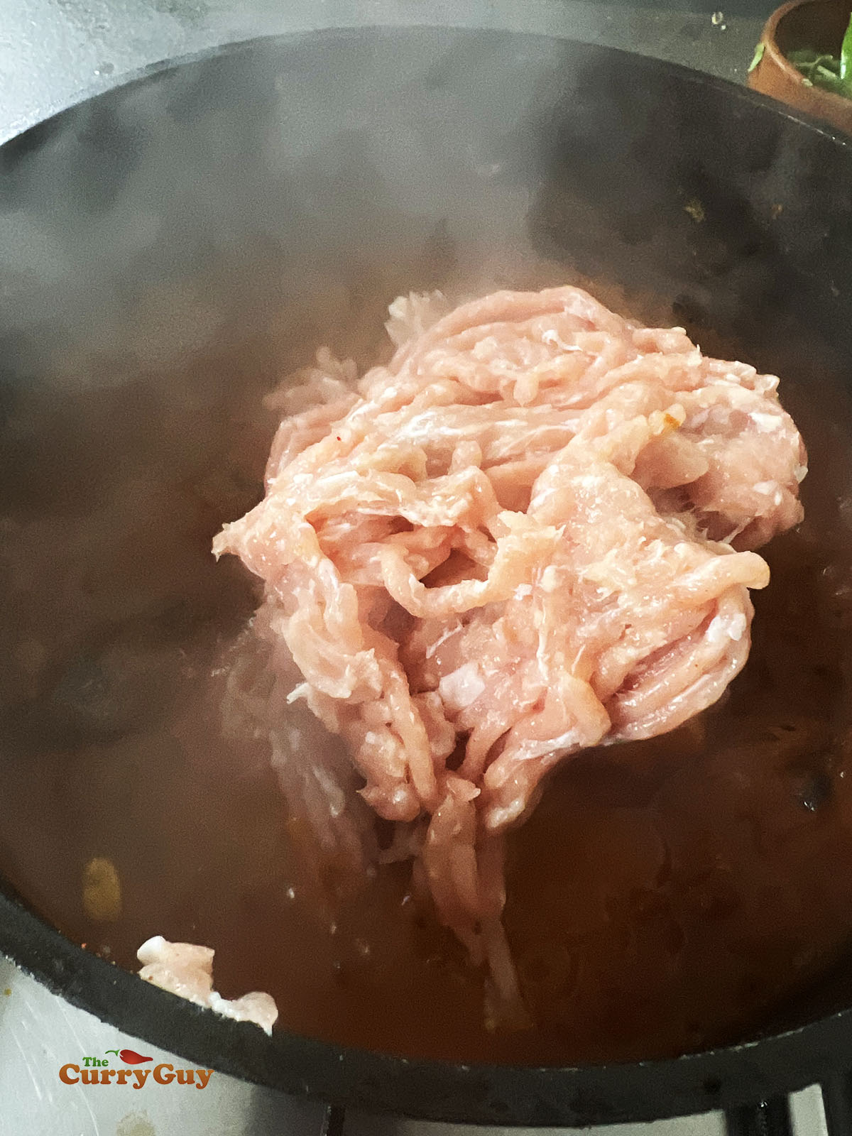Adding minced (ground) meat to the pan.