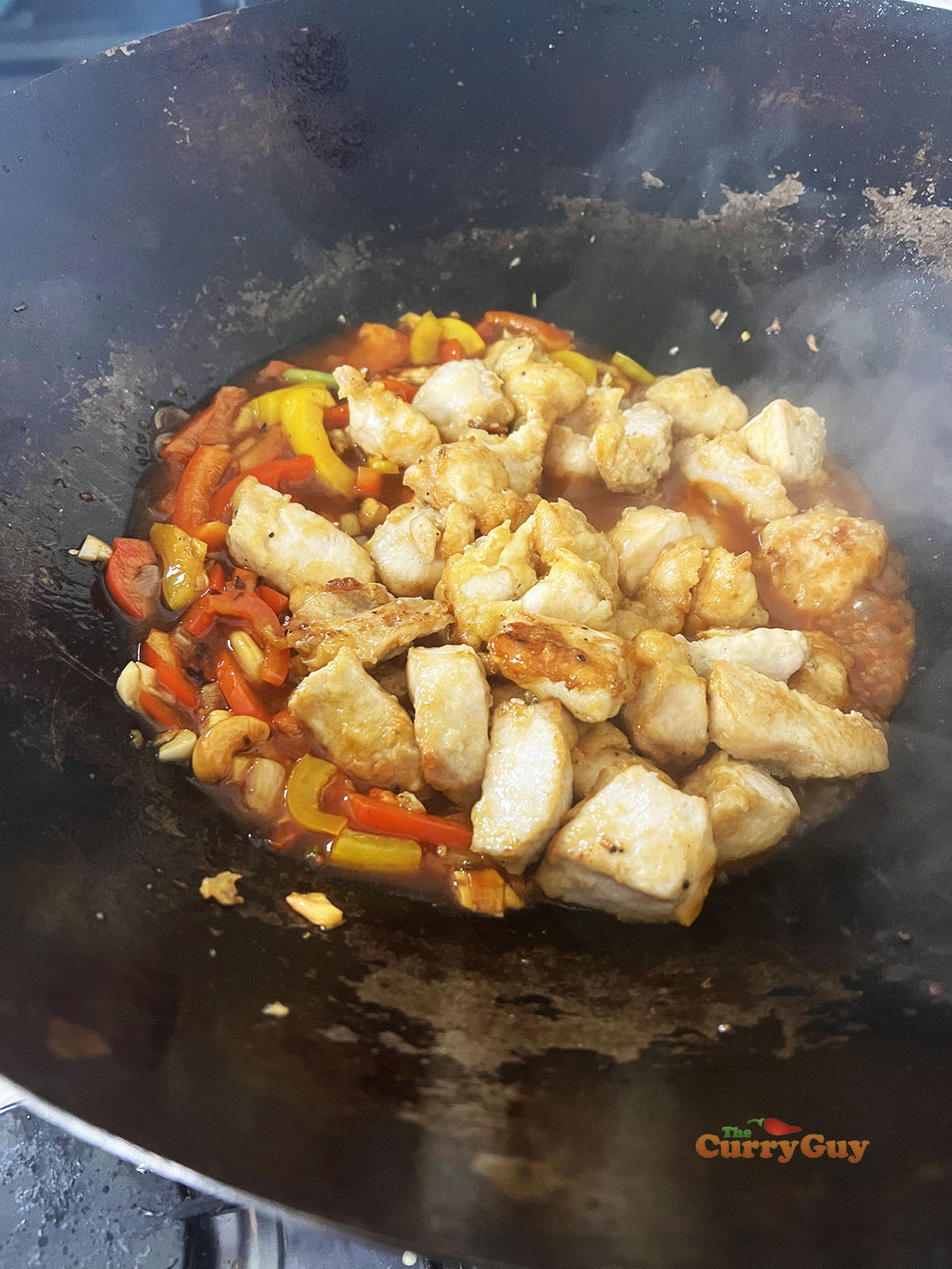 Returning the chicken to the wok.