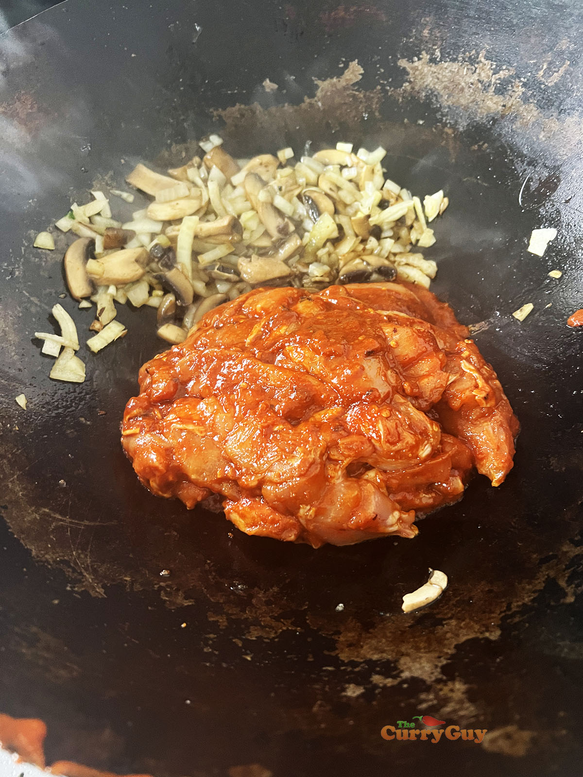 Adding marinated chicken to the wok.