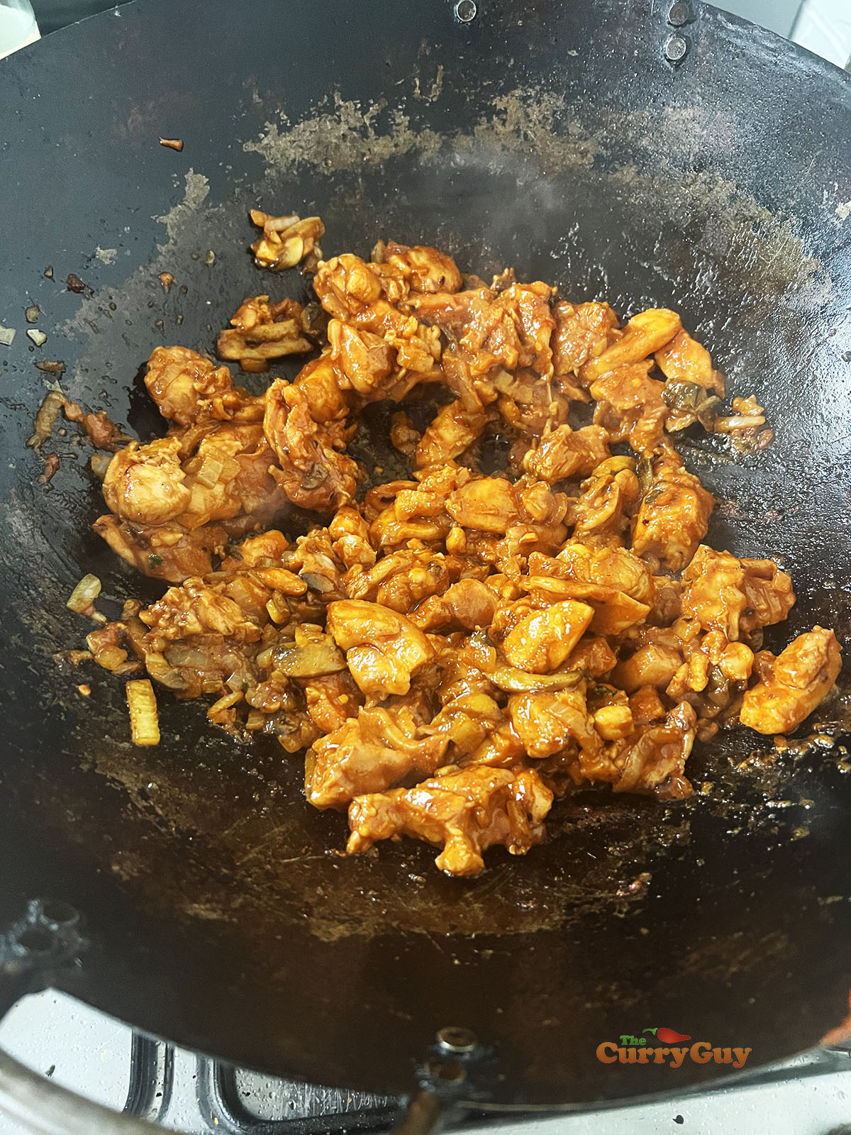 Cooking the chicken and marinade with the onions and mushrooms in the wok.