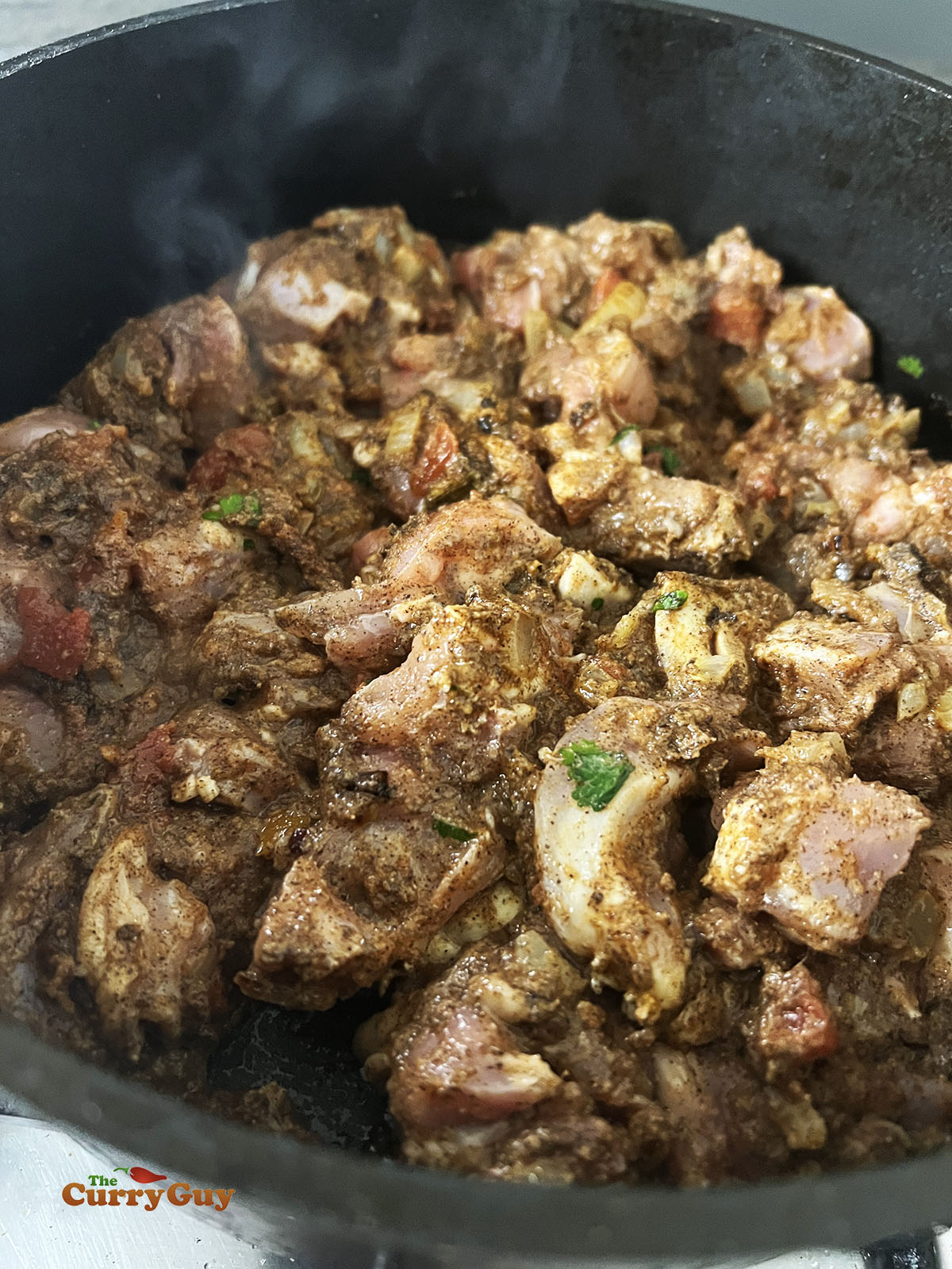 Stirring the chicken into the spices in the pan.