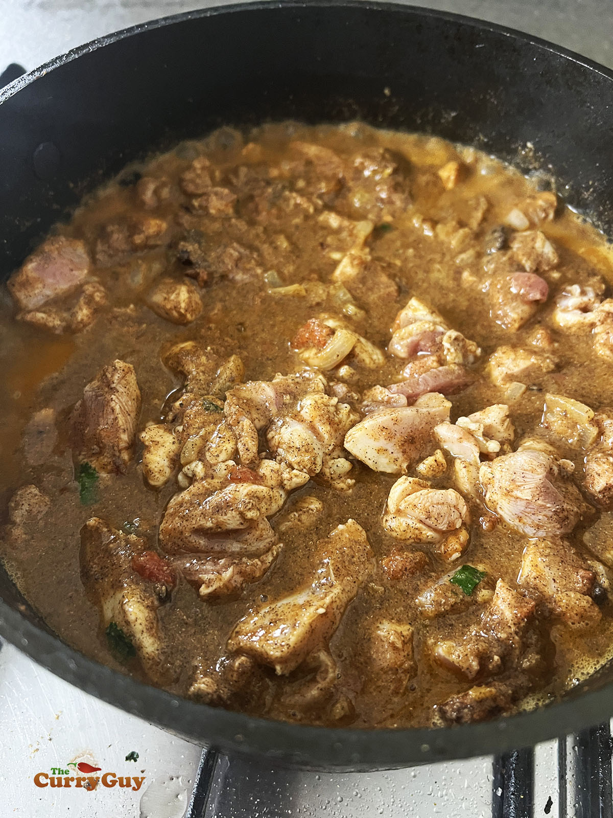 Adding water to the chicken in the pan.