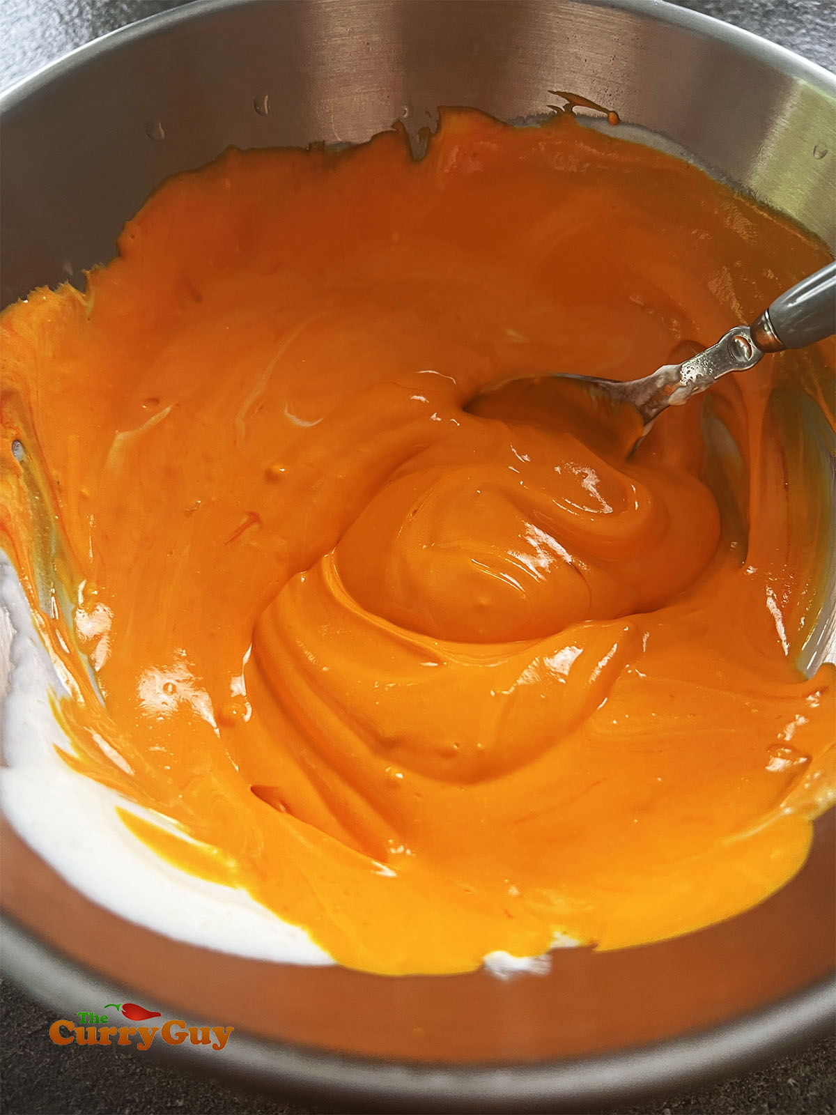 Whisking the orange food colouring with yoghurt. You can also mix the colouring with water.