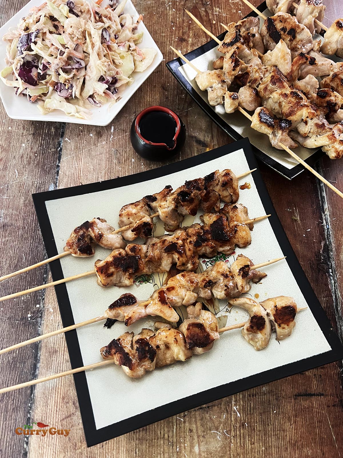 Finished teriyaki chicken served on skewers on a plate.
