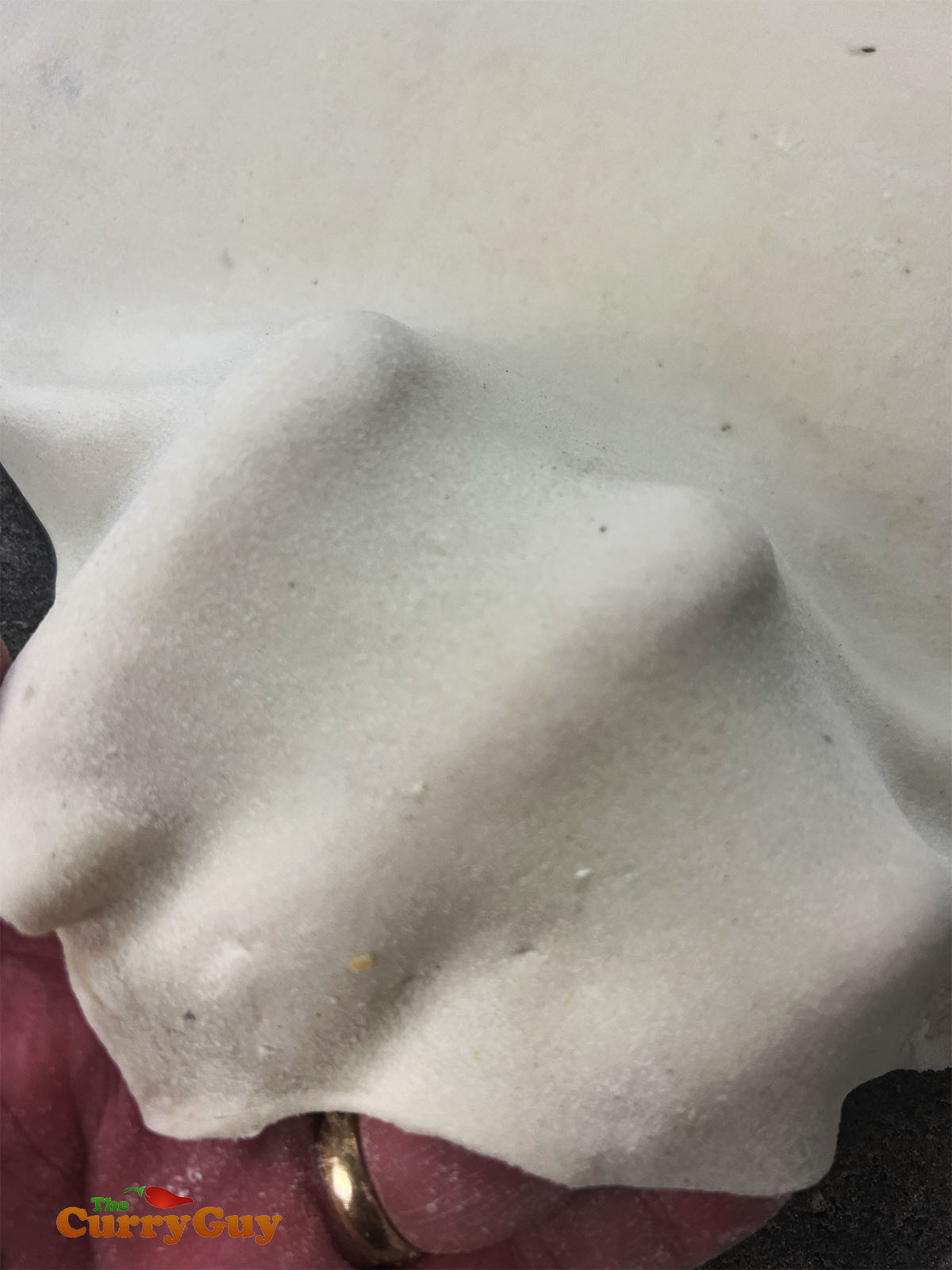 Showing fingers through the rolled out dough so that people can see how thin it is. 