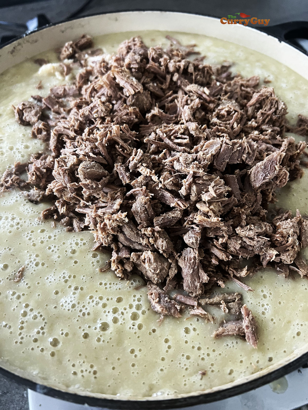 Adding the spice blend, the shredded meat and bone marrow to the sauce.