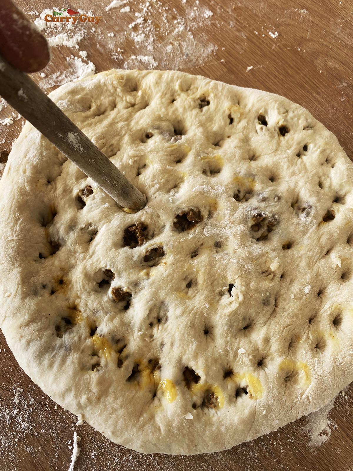 Making holes over the surface of the curry stuffed naan.