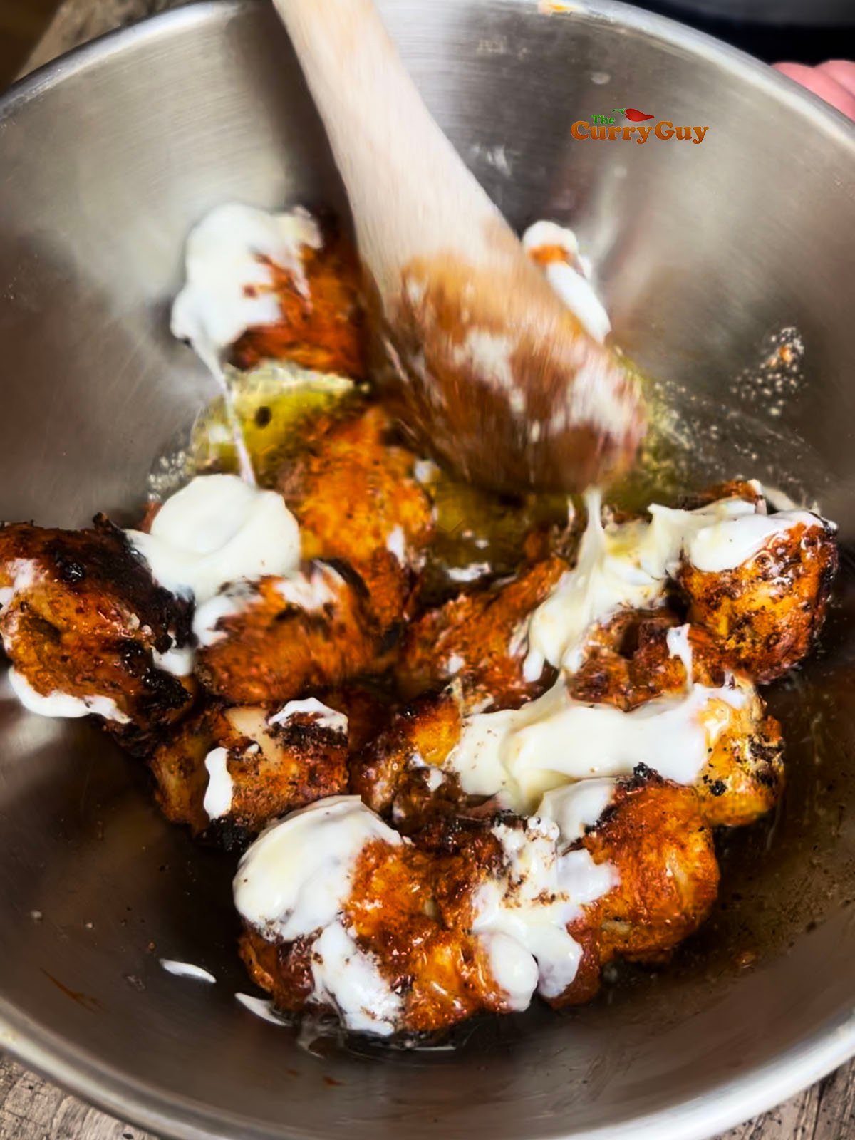 Stirring ghee, yoghurt and chaat masala into the tandoori chicken