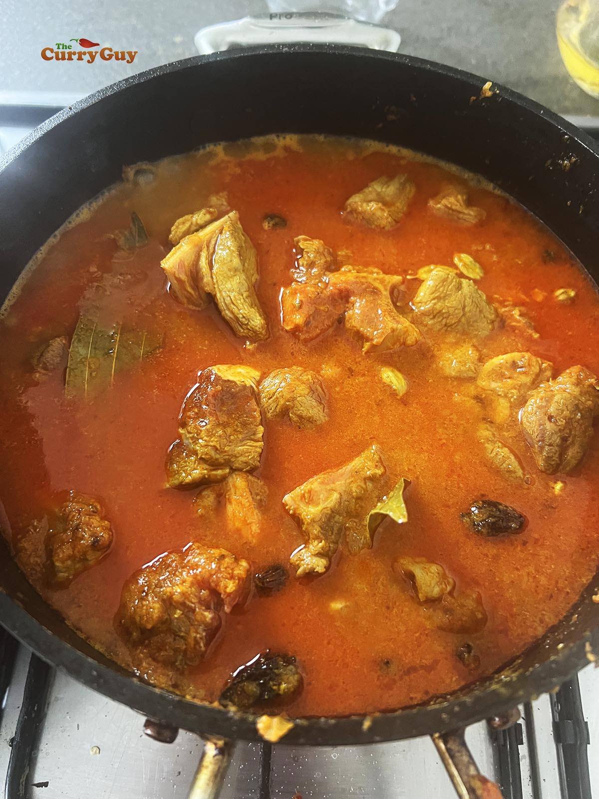 Adding water to the pan to simmer and cook the meat.