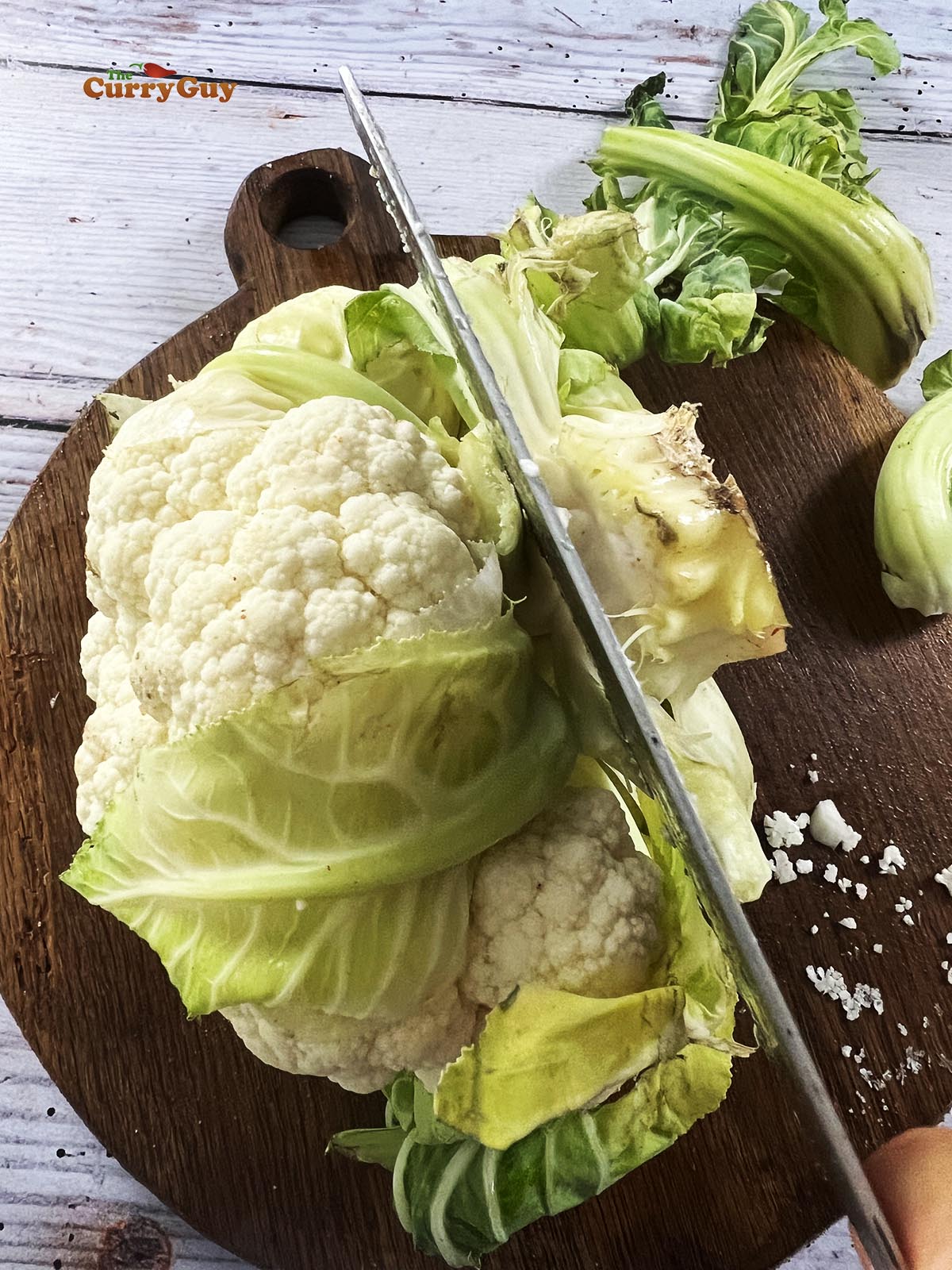 Slicing off the green leaves and stem of the cauliflower