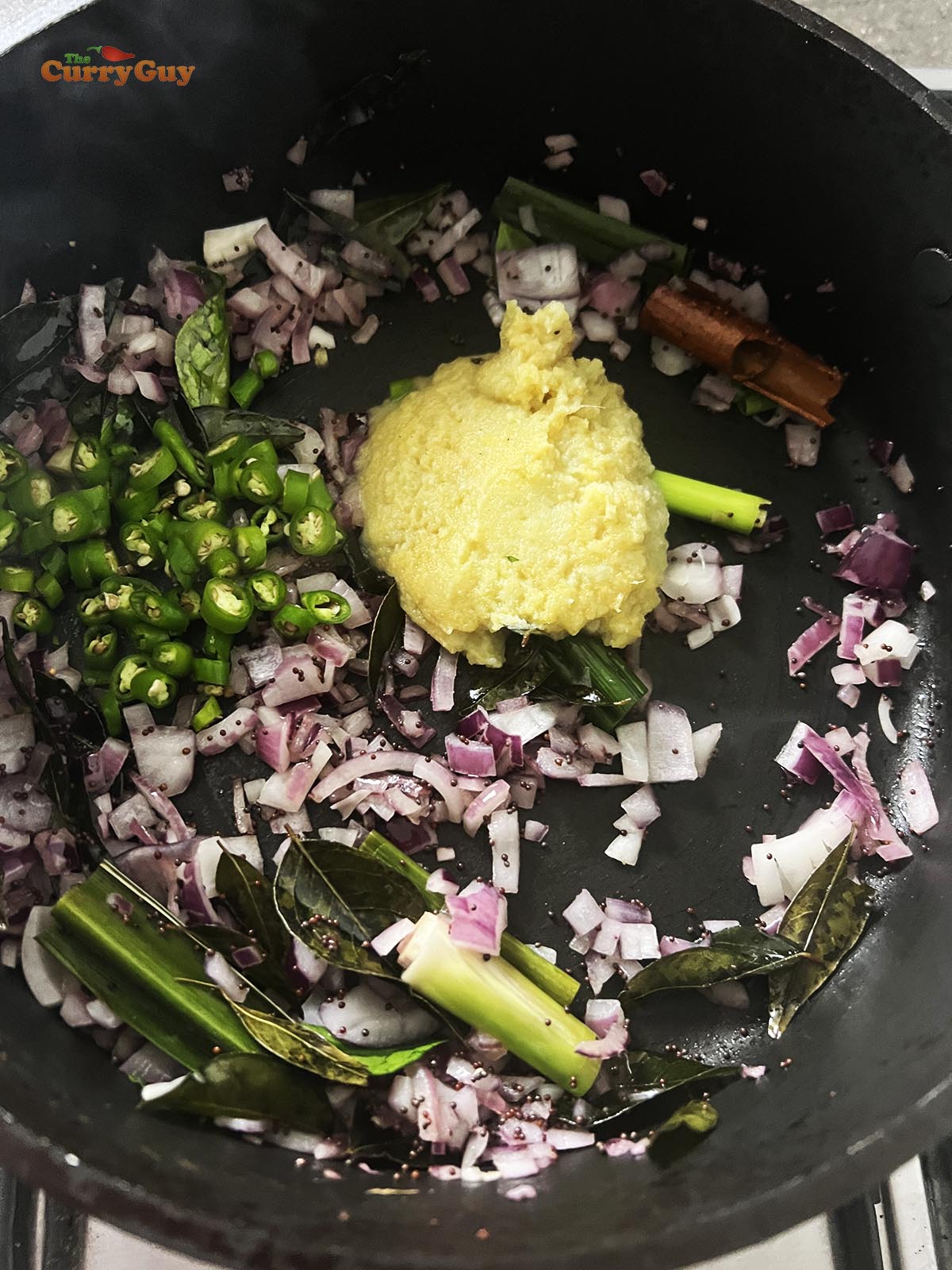 Adding chopped onions, garlic and ginger paste and chillies to the pan.
