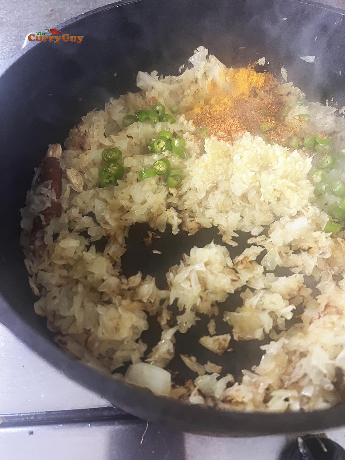 Adding garlic and ginger paste, chillies and ground spices to the pan.