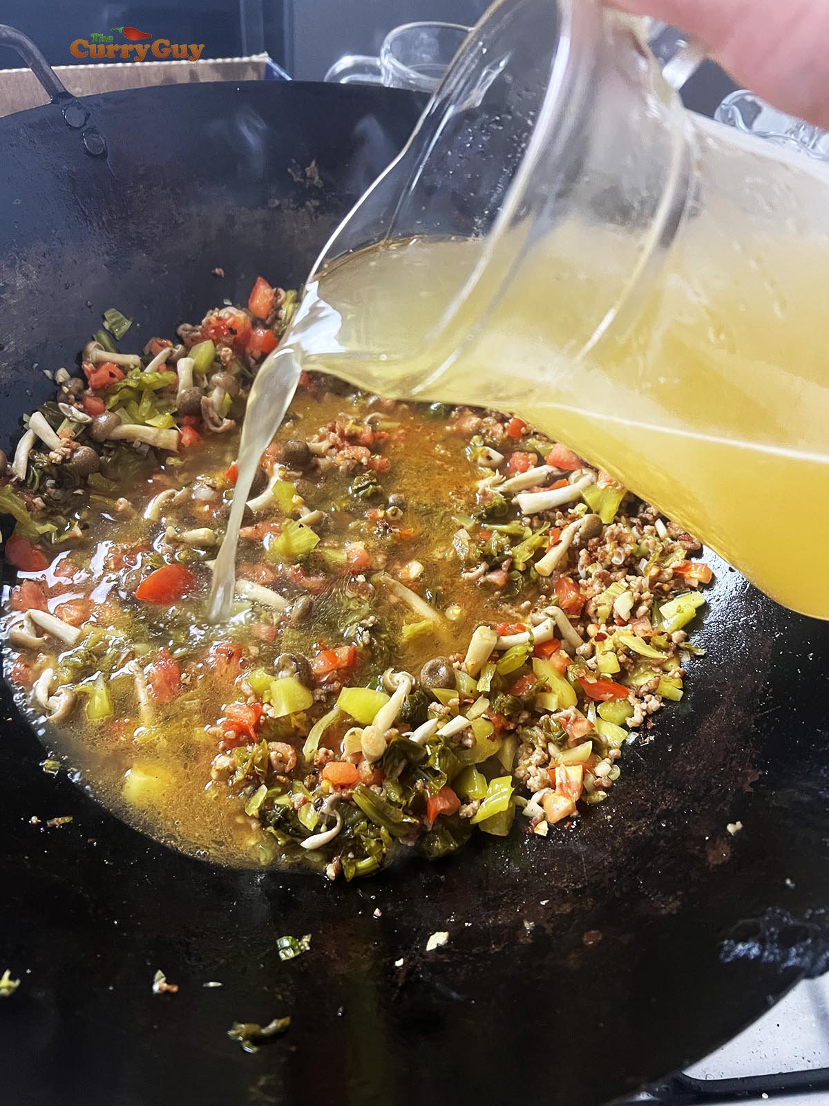 Pouring the stock into the wok.