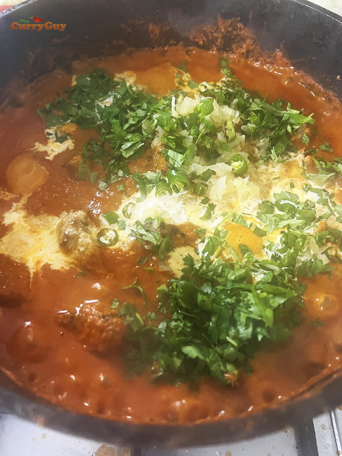 Adding coriander (cilantro), cream and butter to the sauce.