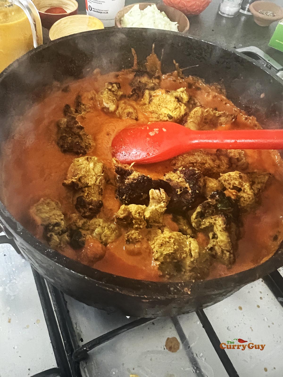 Adding tandoori chicken to the bubbling sauce.