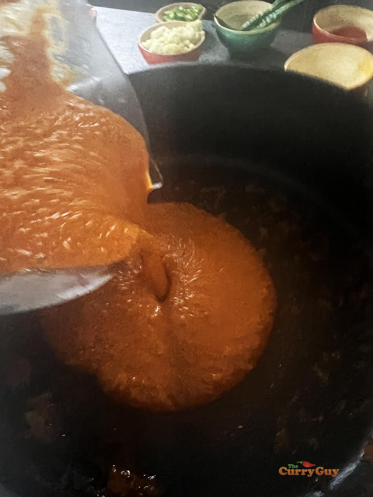 Adding the blended sauce back to the pan and bringing to a simmer.