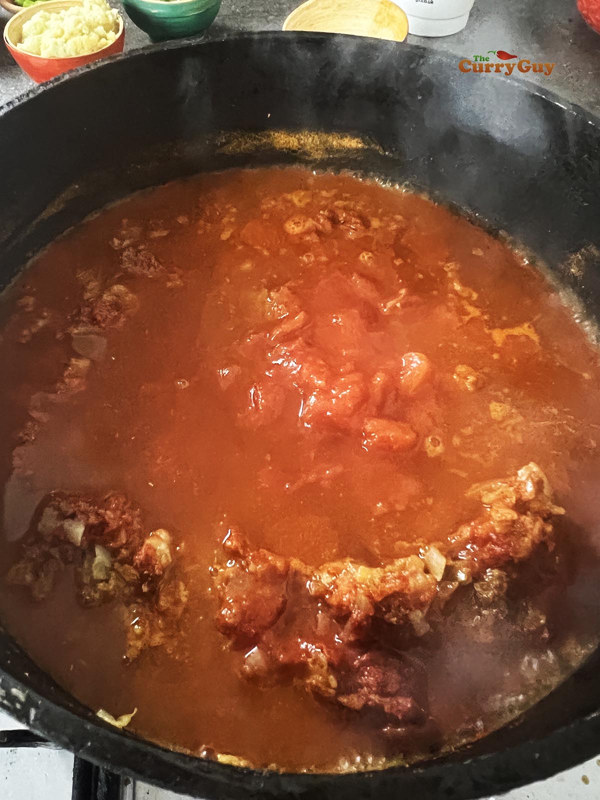 Adding chopped tomatoes and stock/water to the pan.